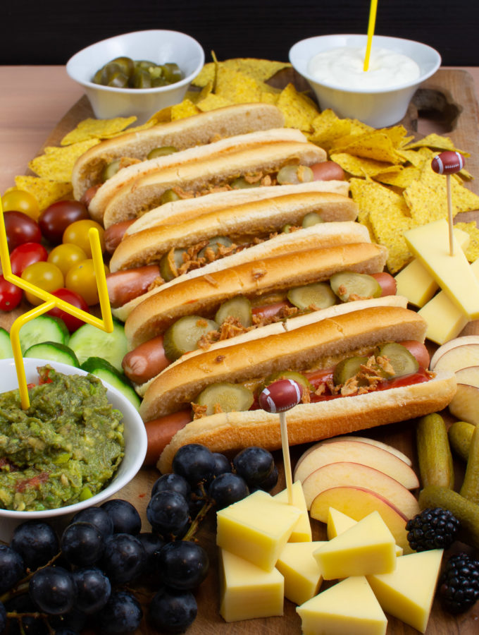 Hot Dog Charcuterieplatte mit klassischen Hot Dogs, Nachos, Dips, Käse und jeder Menge Obst und Gemüse