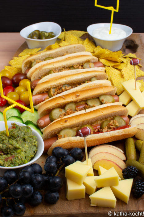 Hot Dog Charcuterieplatte mit klassischen Hot Dogs, Nachos, Dips, Käse und jeder Menge Obst und Gemüse